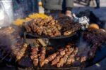 Delicious meat skewers grilling over an open fire at an outdoor BBQ.