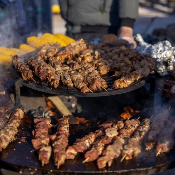 Delicious meat skewers grilling over an open fire at an outdoor BBQ.