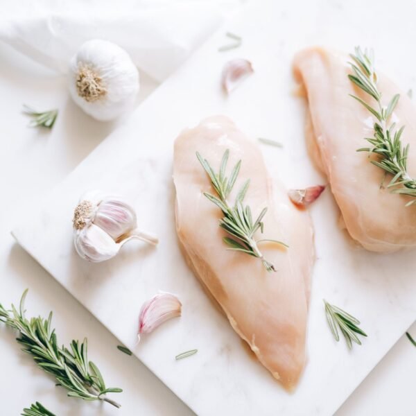 Top view of raw chicken breasts with rosemary and garlic, perfect for culinary ideas.